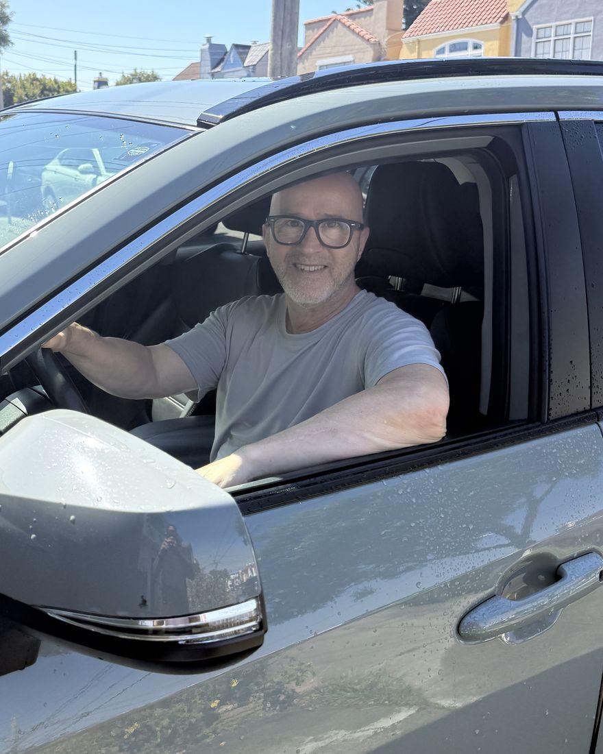 Jeronimo Dias, motorista brasileiro em San Francisco, sorrindo ao volante do seu Toyota RAV4